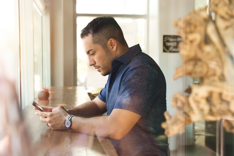 Man looking at phone, sitting at counter